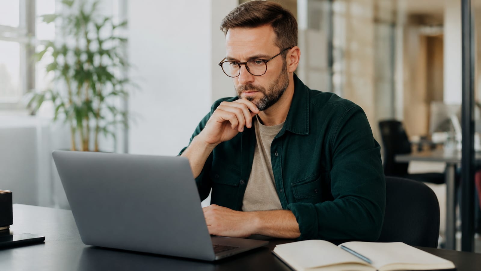 Un professionista rivede il proprio lavoro al laptop con espressione attenta e valutativa