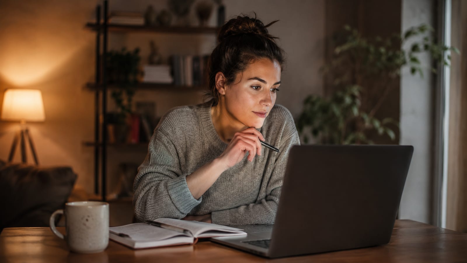 Una persona impara l'inglese al laptop in un ambiente rilassato, con quaderno e caffè accanto
